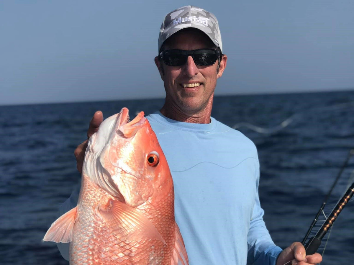 Angler holding a large red fish aboard a boat
