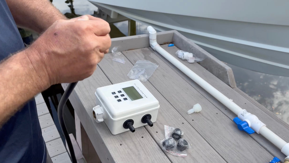 Hands assembling a Flushmaster Controller and plumbing setup