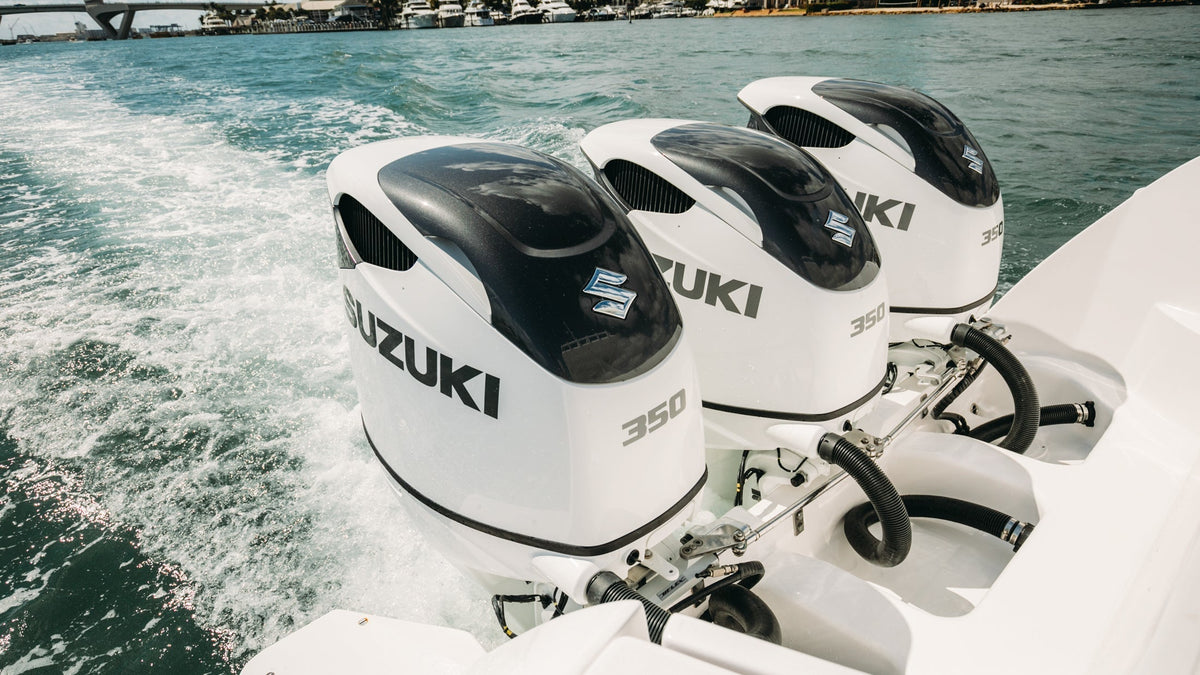 White Suzuki outboards at the stern of a boat underway