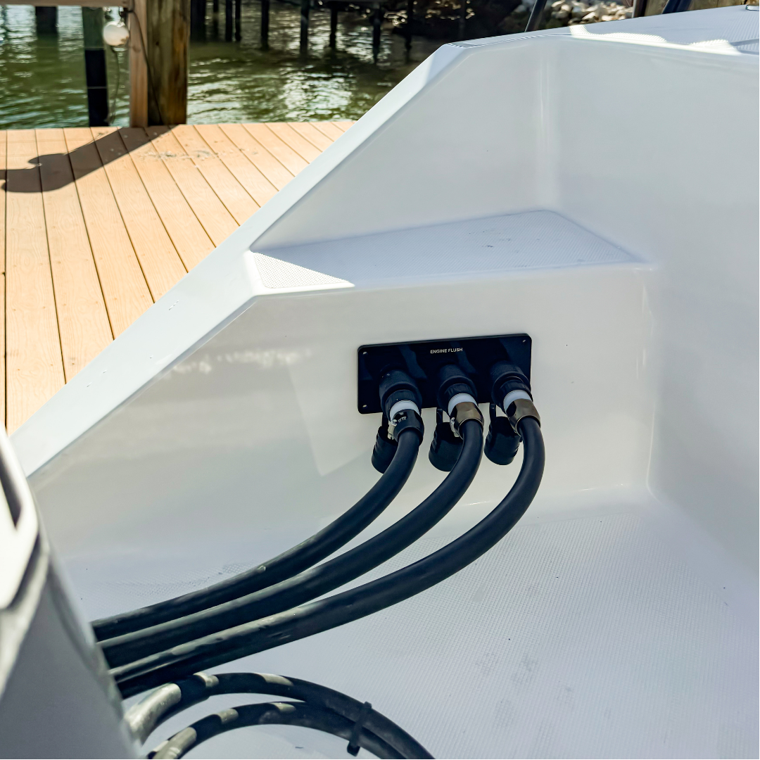 flushing hoses connected to black acrylic flush port reroute plate on white boat by dock