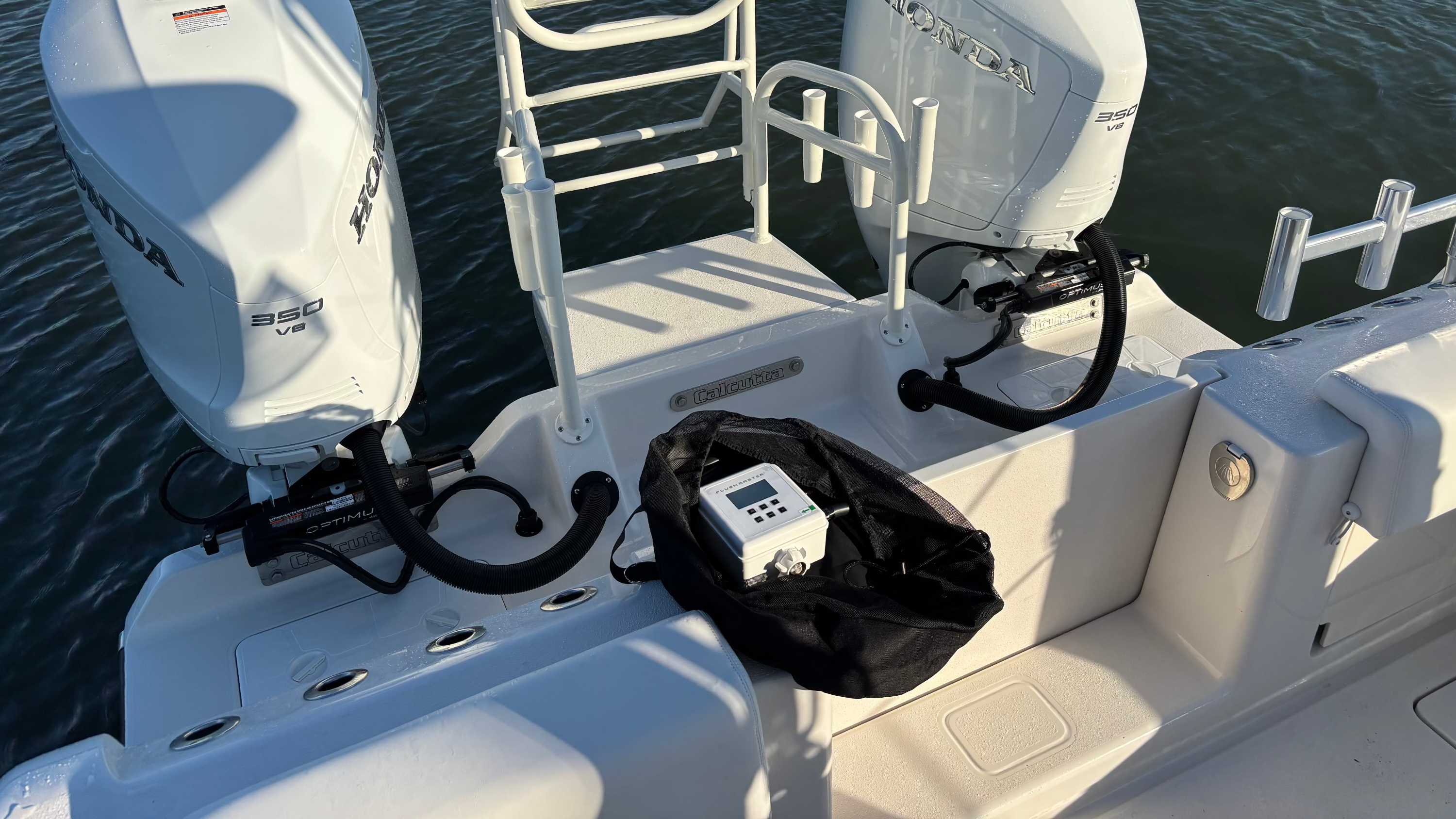 flushmaster sitting inside portable storage bag with hose kits on transom of dual honda boat