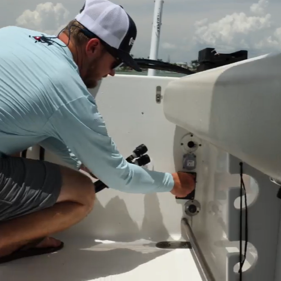 man connecting flush hoses to dual port black acrylic reroute inside the boat