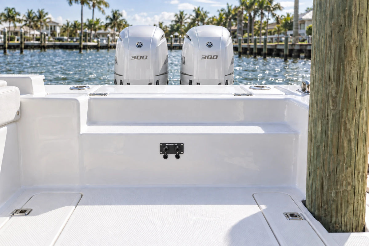 Illustrated black 2-outlet Flush Port Reroute mounted horizontally in a boat cockpit with 2 outboard engines and open locking caps