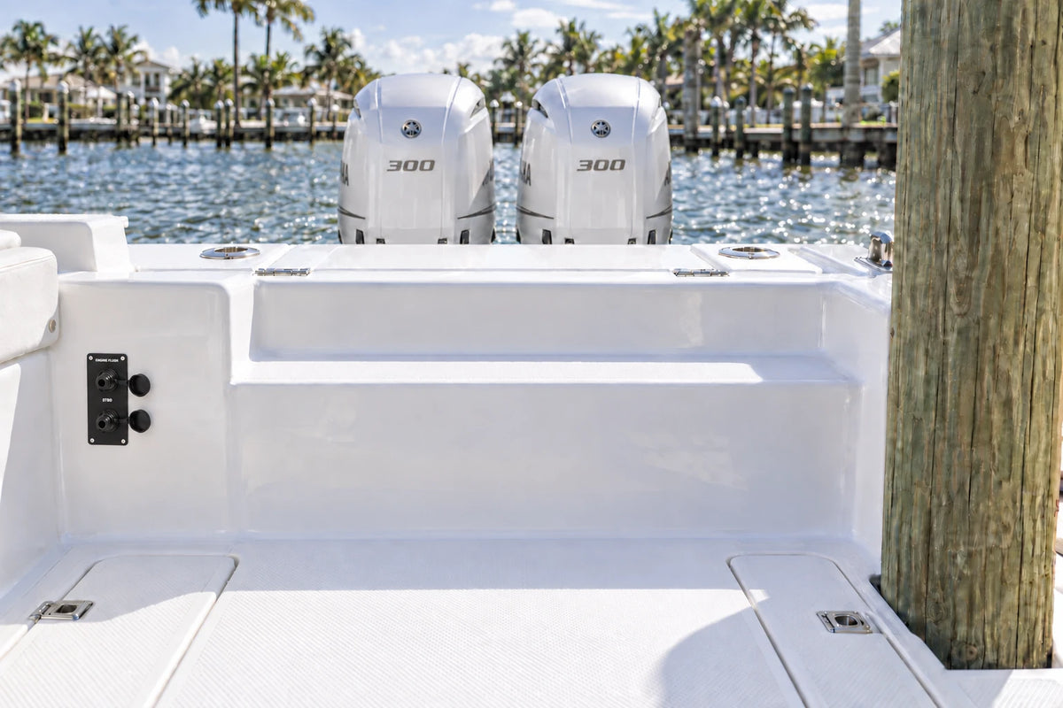 Illustrated black 2-outlet Flush Port Reroute mounted vertically in a boat cockpit with 2 outboard engines and open locking caps