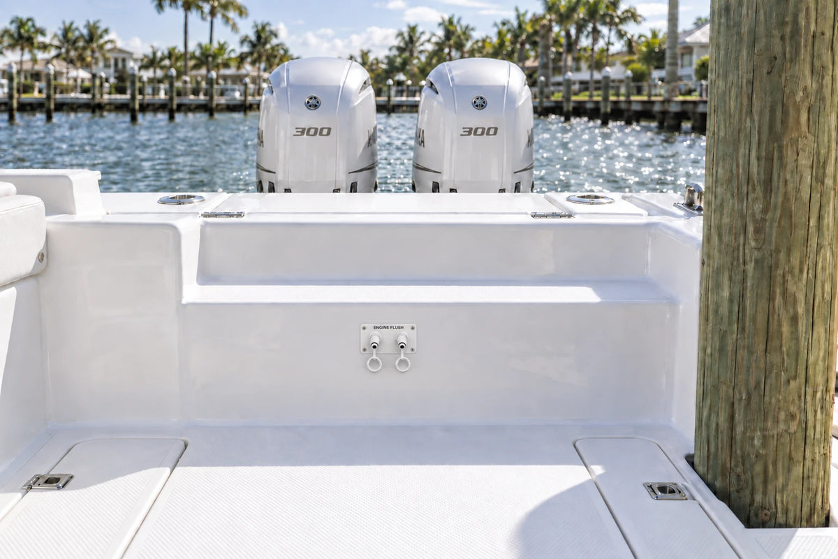 Illustrated white 2-outlet Flush Port Reroute mounted horizontally in a boat cockpit with 2 outboard engines and open locking caps