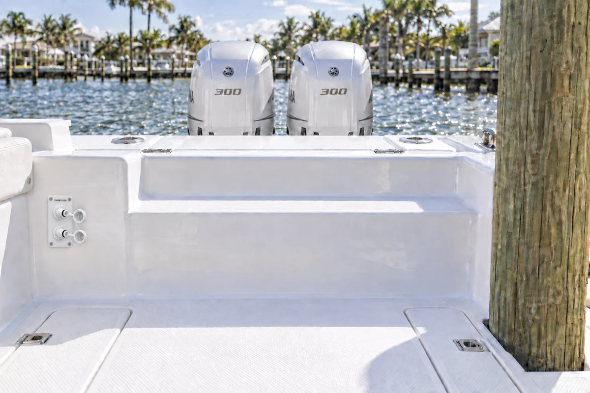 Illustrated white 2-outlet Flush Port Reroute mounted vertically in a boat cockpit with 2 outboard engines and open locking caps