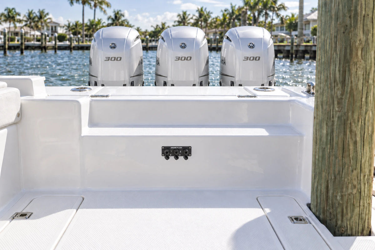 Illustrated black 3-outlet Flush Port Reroute mounted horizontally in a boat cockpit with 3 outboard engines and open locking caps