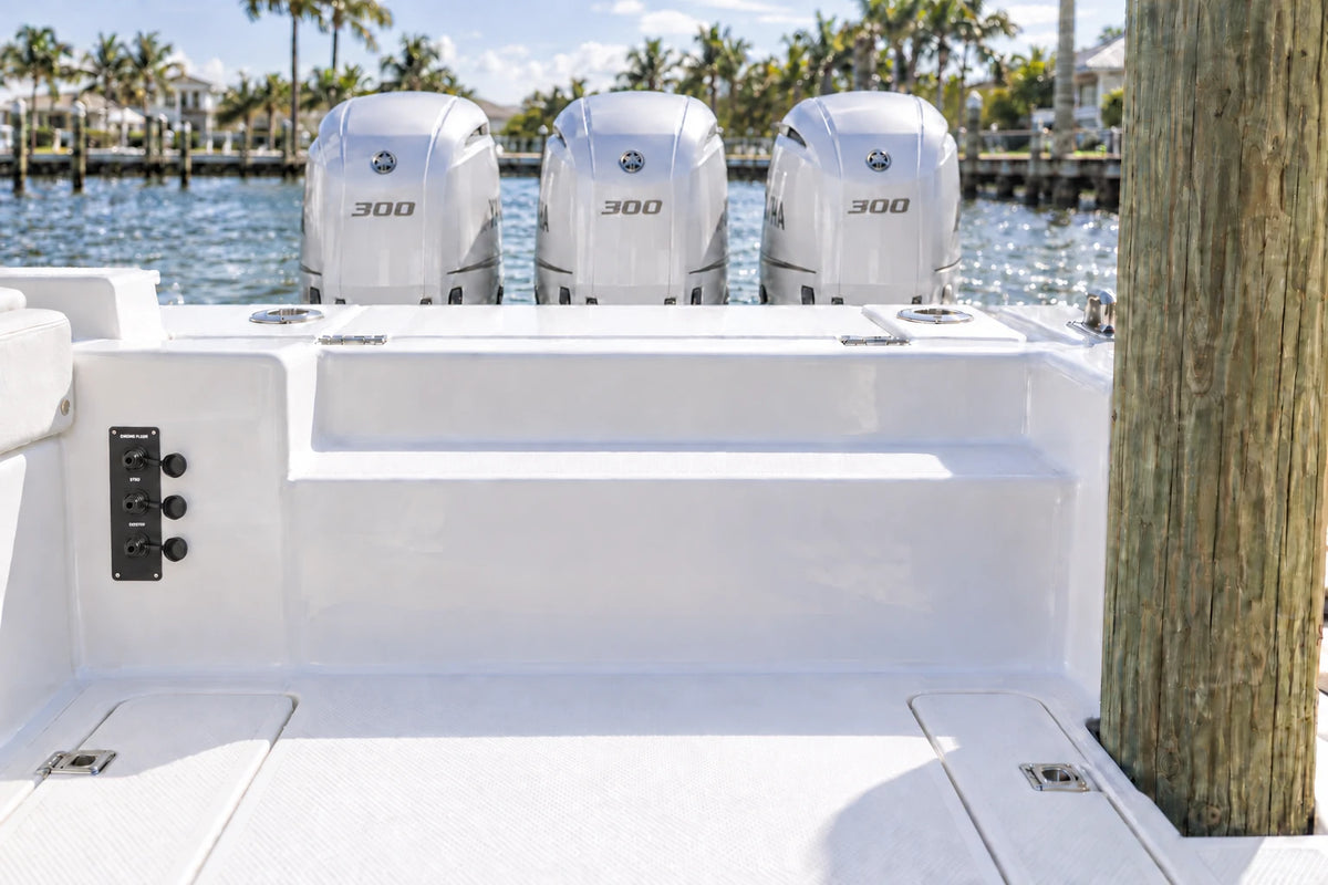 Illustrated black 3-outlet Flush Port Reroute mounted vertically in a boat cockpit with 3 outboard engines and open locking caps