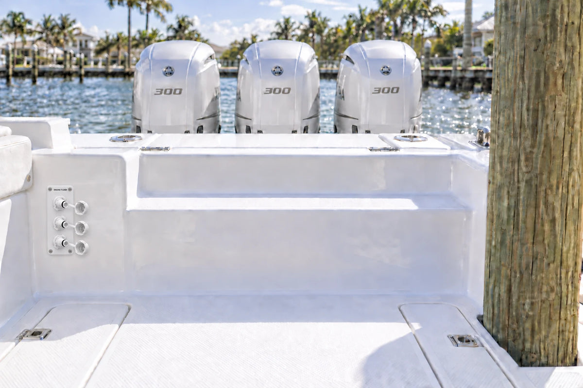 Illustrated white 3-outlet Flush Port Reroute mounted vertically in a boat cockpit with 3 outboard engines and open locking caps