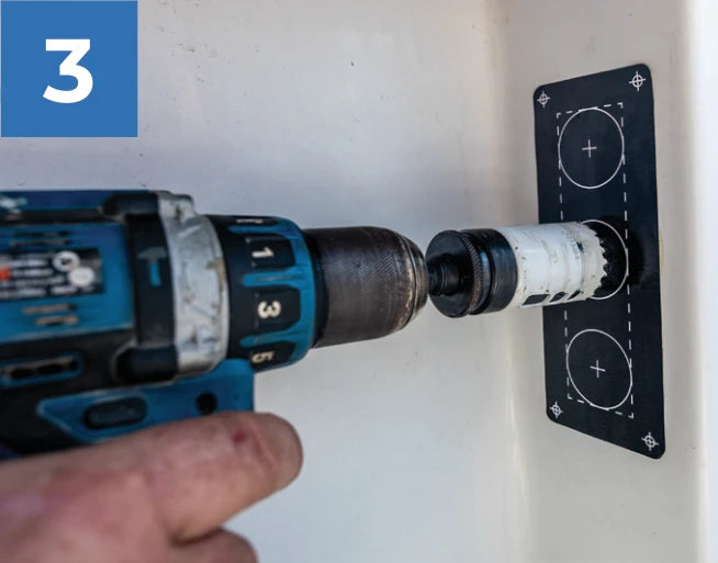 A hole saw aligned with a plumbing cutout on the mounting template.