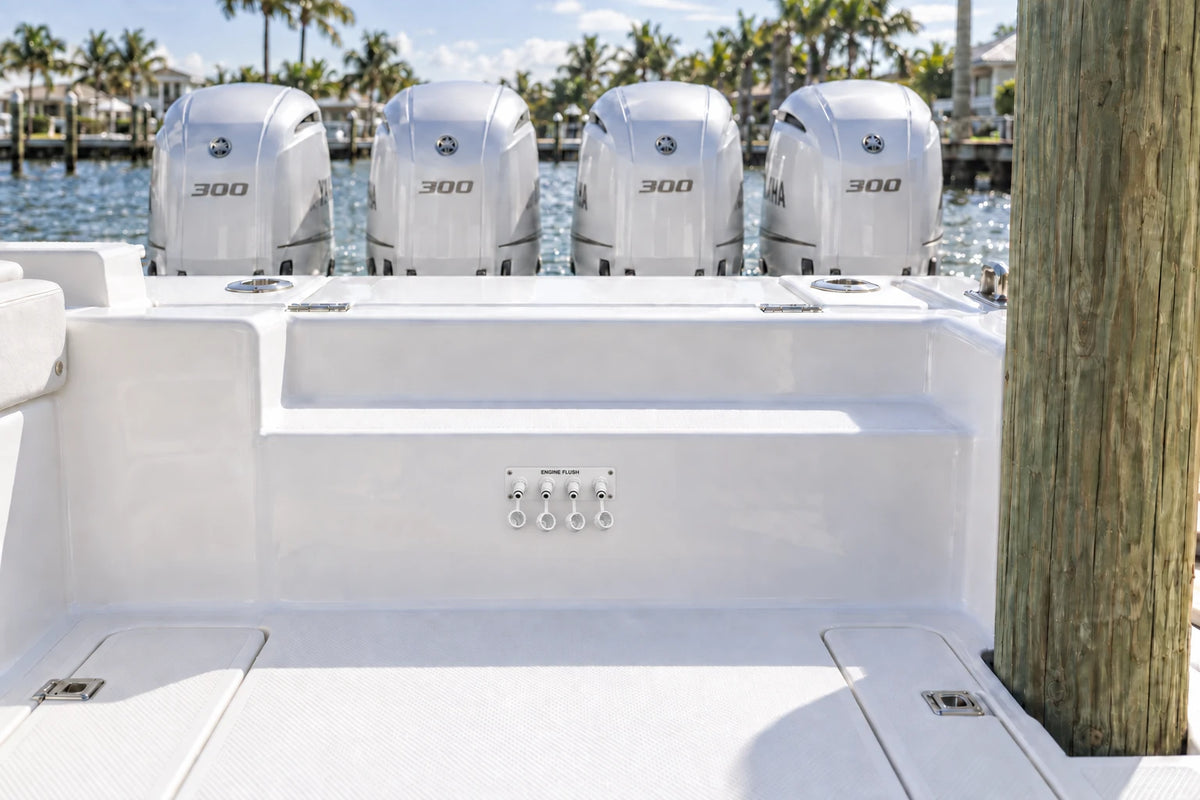 Illustrated white quad Flush Port Reroute plate mounted horizontally on the aft cockpit step, with open tethered locking caps and four outboards behind the transom