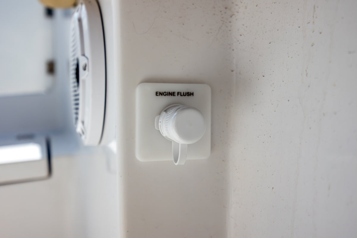 Single white Flush Port Reroute shown on a boat beside a speaker, with its locking cap closed.