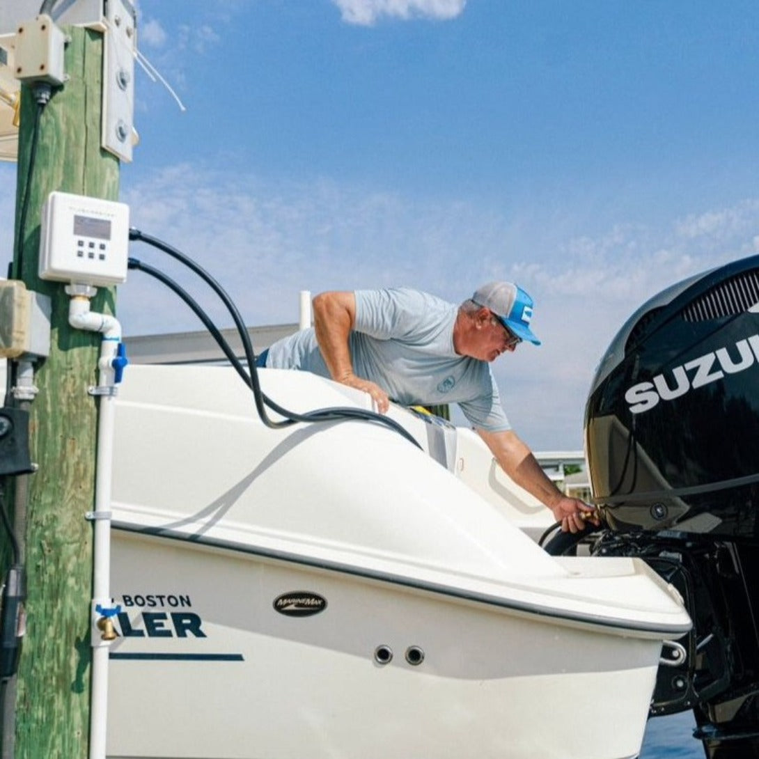 Flushmaster system efficiently flushing dual Suzuki motors on a Boston Whaler boat near a dock, showcasing optimal engine maintenance in a real-world marine setting.