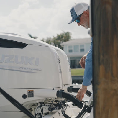 man connecting flushmaster flush hoses to dual suzuki outboards using quick connects