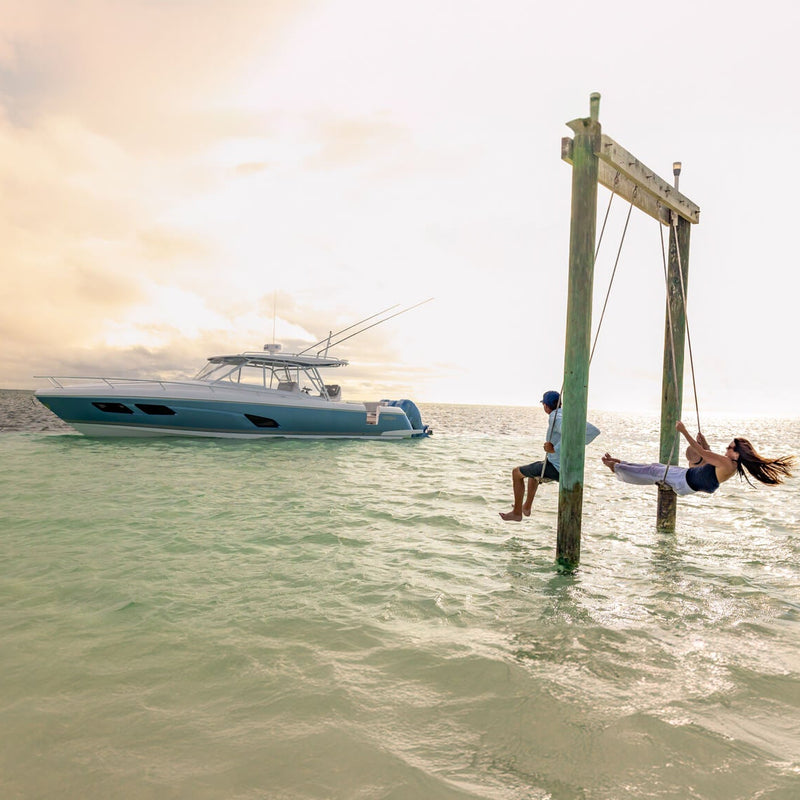 couple swinging above water near boat